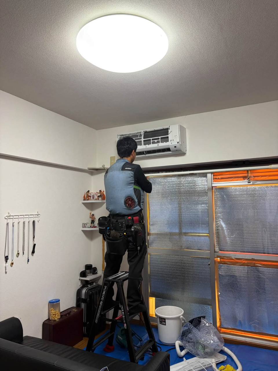 室内を養生して壁掛けエアコンを分解洗浄している作業風景